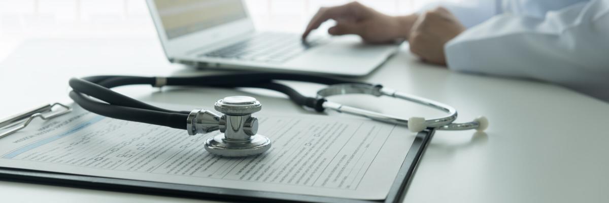 HIPAA Compliance concept, medical documents with a stethoscope on top with a laptop in the background