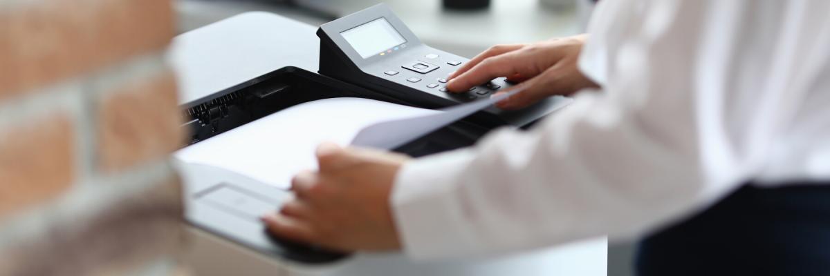 Business man standing at a printer, waiting for the feed to print