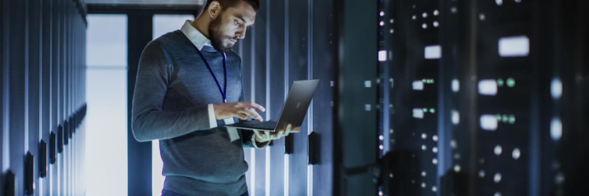 man on computer in server room