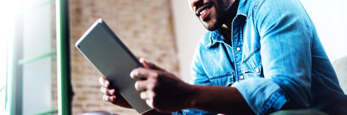 Smiling man using tablet device to access Central Business Solutions support